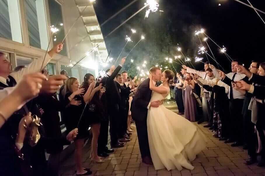 A bride and groom kissing with sparklers in front of their guests, creating an unforgettable wedding experience.