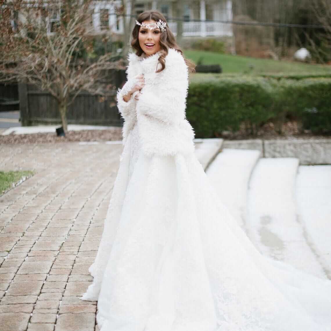 A bride in a white wedding dress and fur coat.