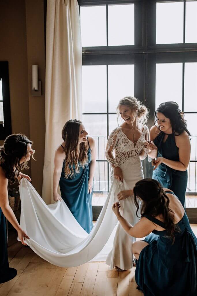 Bridesmaids helping each other put on the wedding dress, enhancing the wedding experience.
