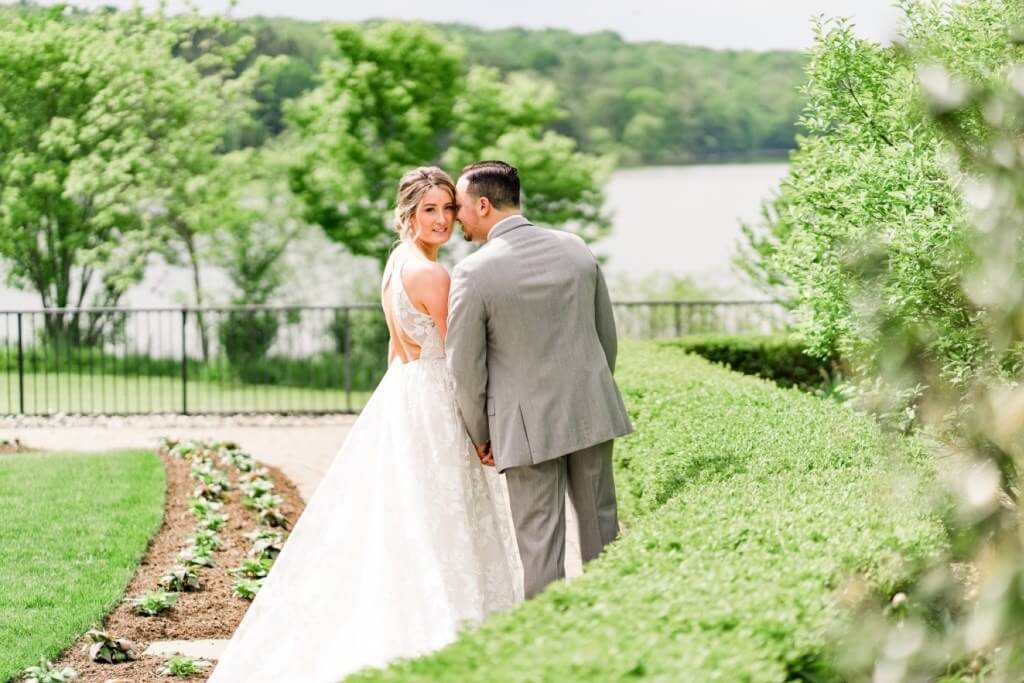 A bride and groom kissing in front of a pond.