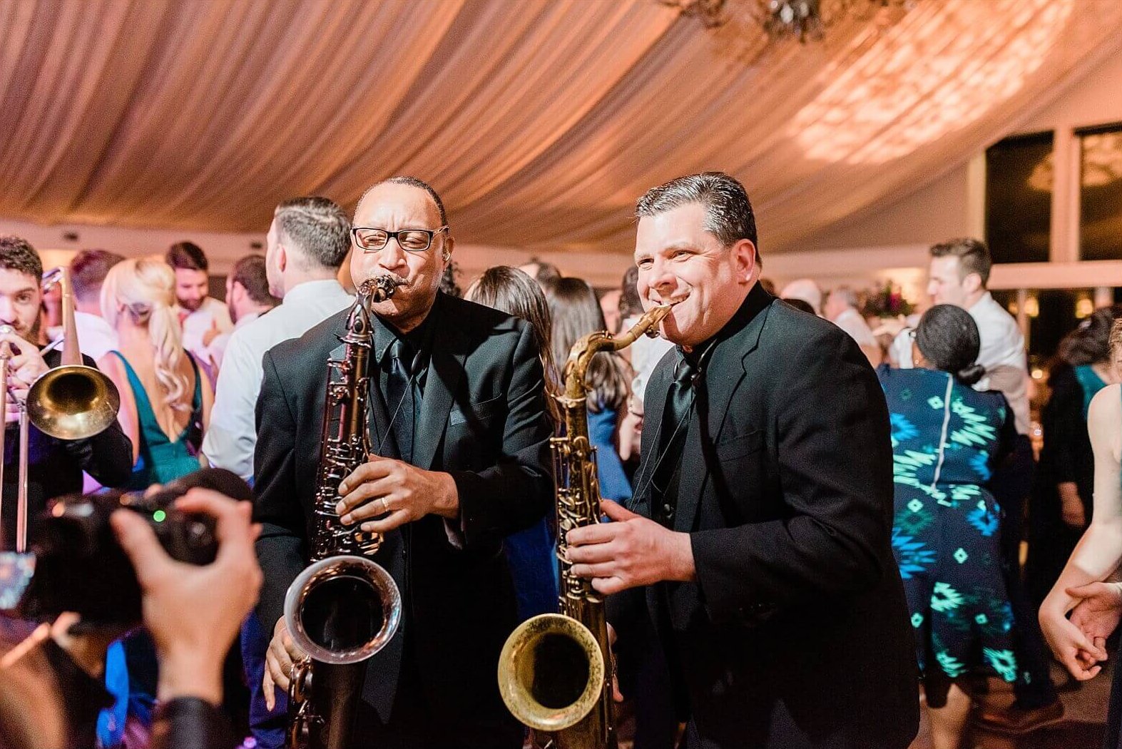 Two men playing saxophones, enhancing the wedding experience at a reception.