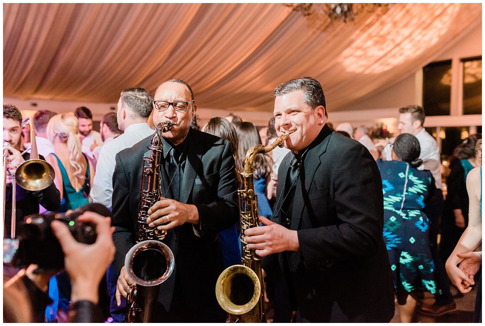 Two men playing saxophones, enhancing the wedding experience at a reception.