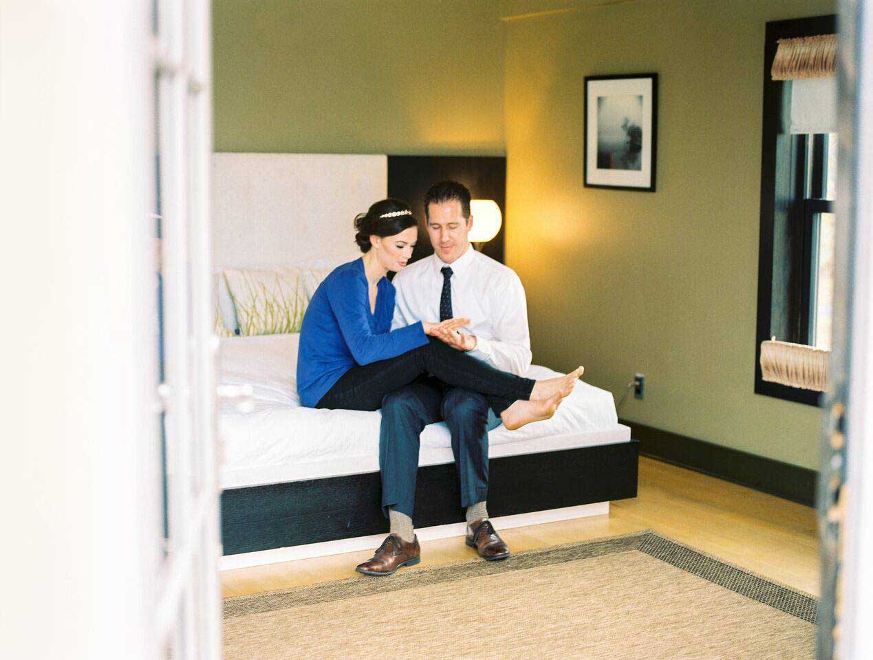 A man and woman staying at the lake house inn, sitting on a bed.