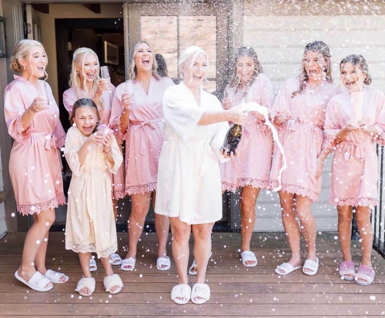 A group of bridesmaids in pink robes holding confetti during a wedding experience.