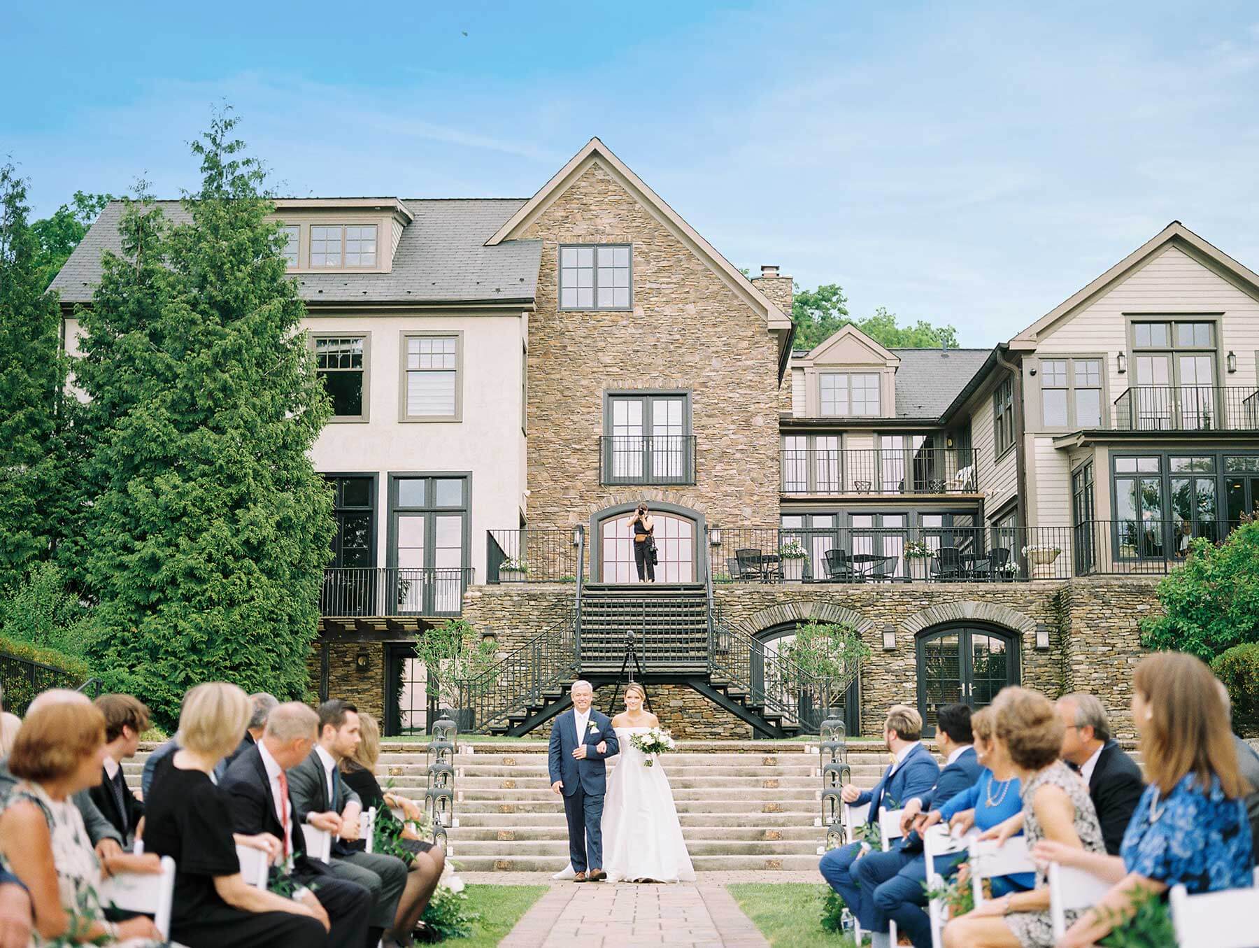 A wedding ceremony in front of a large mansion.