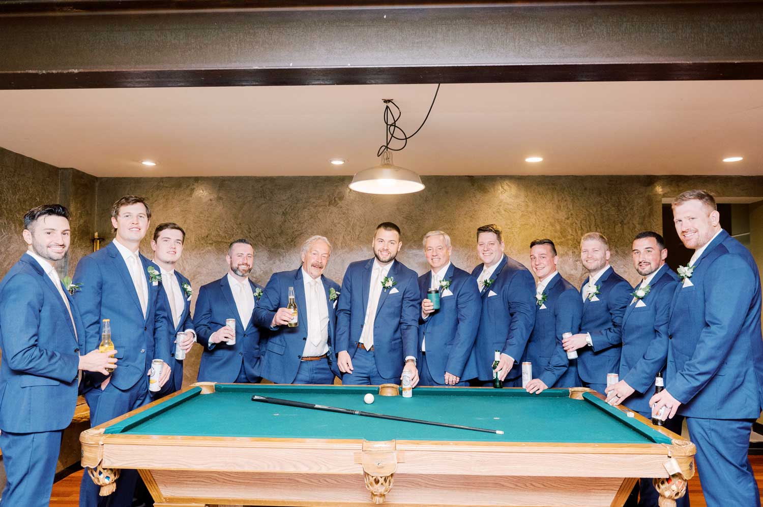 A group of groomsmen posing for a wedding experience picture in front of a pool table.