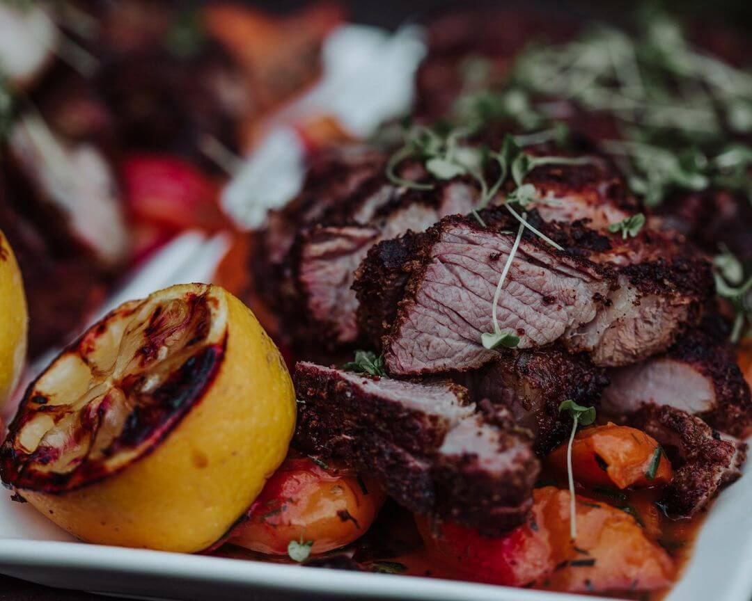 A plate with roasted meat and lemons on it, adding a touch of the wedding experience to your taste.