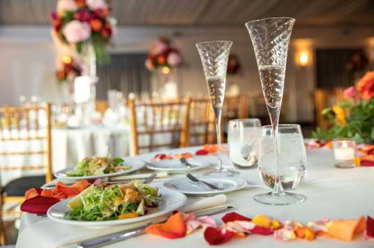 A wedding packages table setting with flowers and a glass of wine.