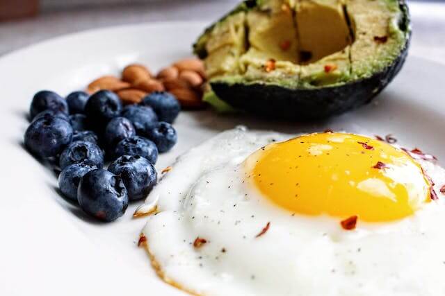 An avocado, blueberries, and an egg on a plate offer a unique wedding breakfast experience.