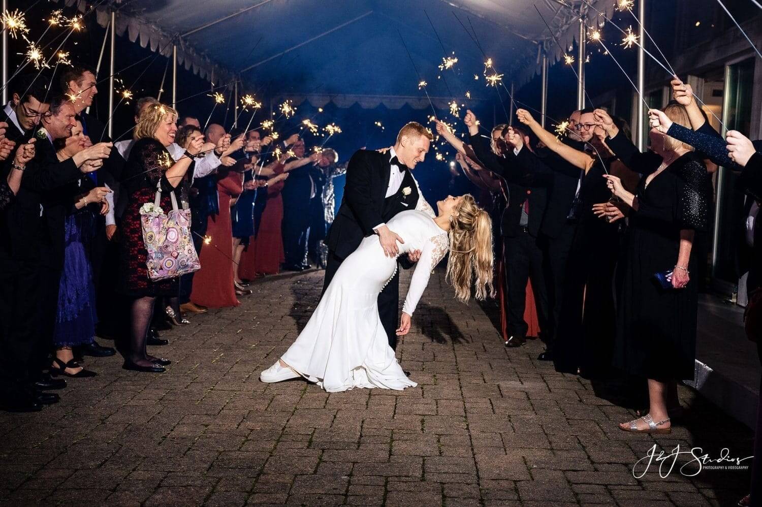 A bride and groom kissing in front of a crowd of sparklers at their wedding packages event.