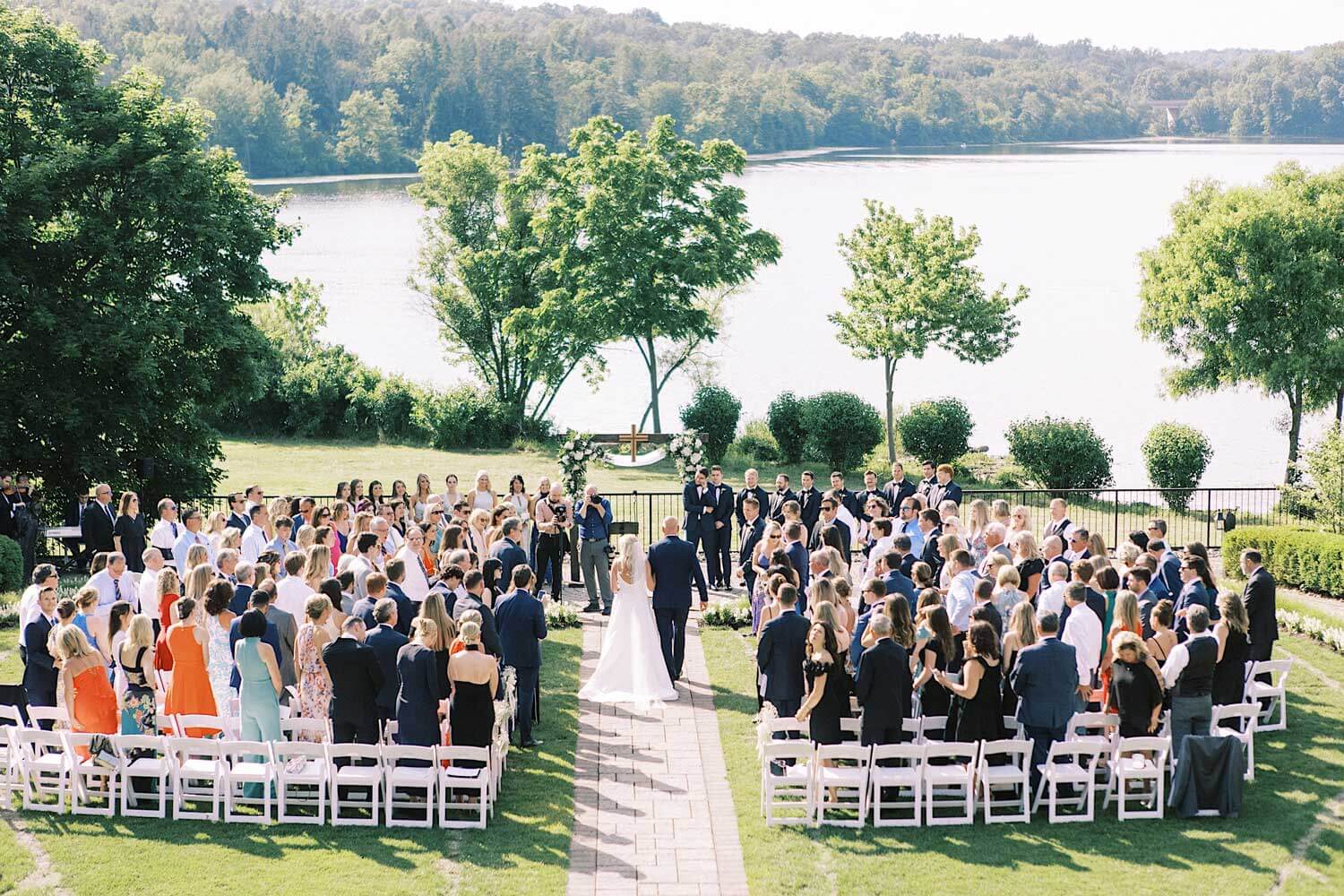 A wedding ceremony on a grassy lawn with a lake in the background.