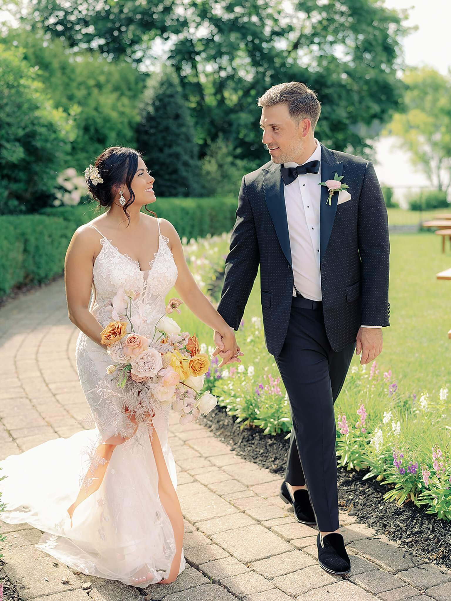 A bride and groom walking down a pathway in a garden, experiencing their wedding.
