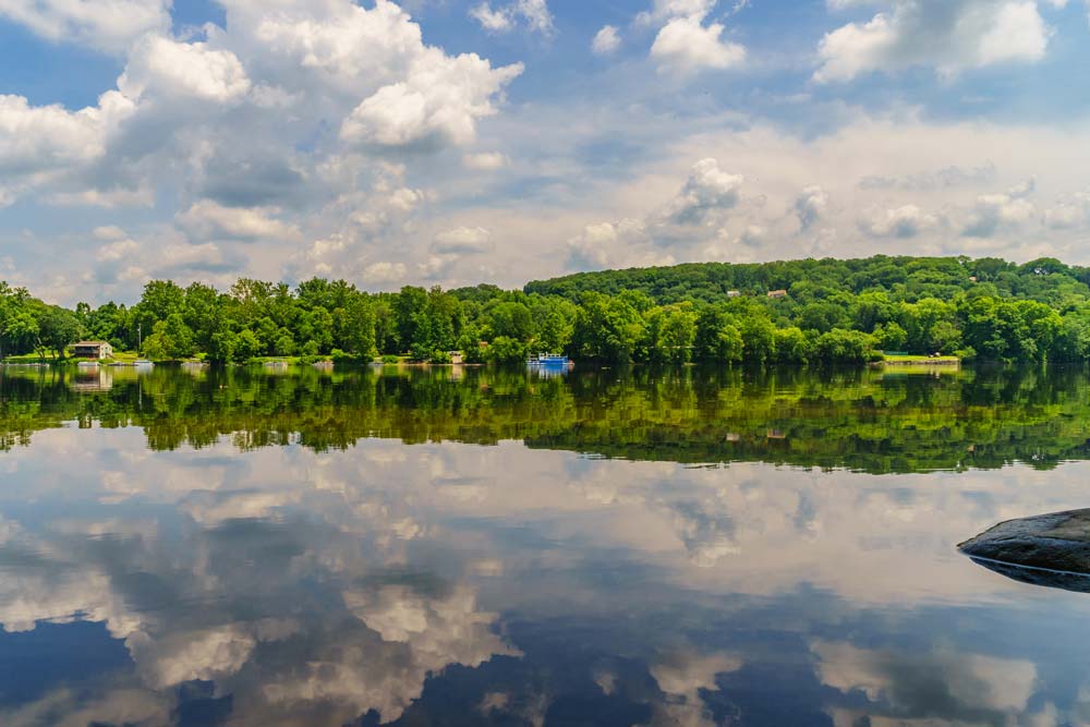 A serene lake reflecting a lush, green forest under a cloudy sky while staying at the Lake House Inn.