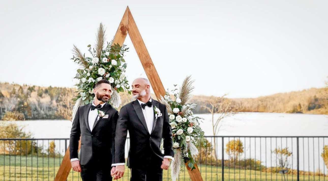 A gay couple exchanging first looks in front of a wedding arch at The Lake House Inn.