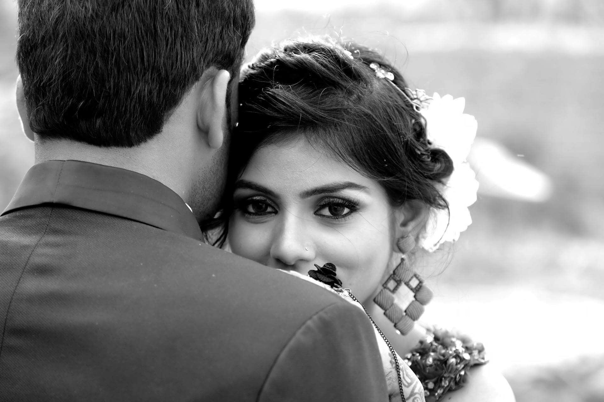 A black and white photo of an Indian bride looking over the shoulder of her groom.