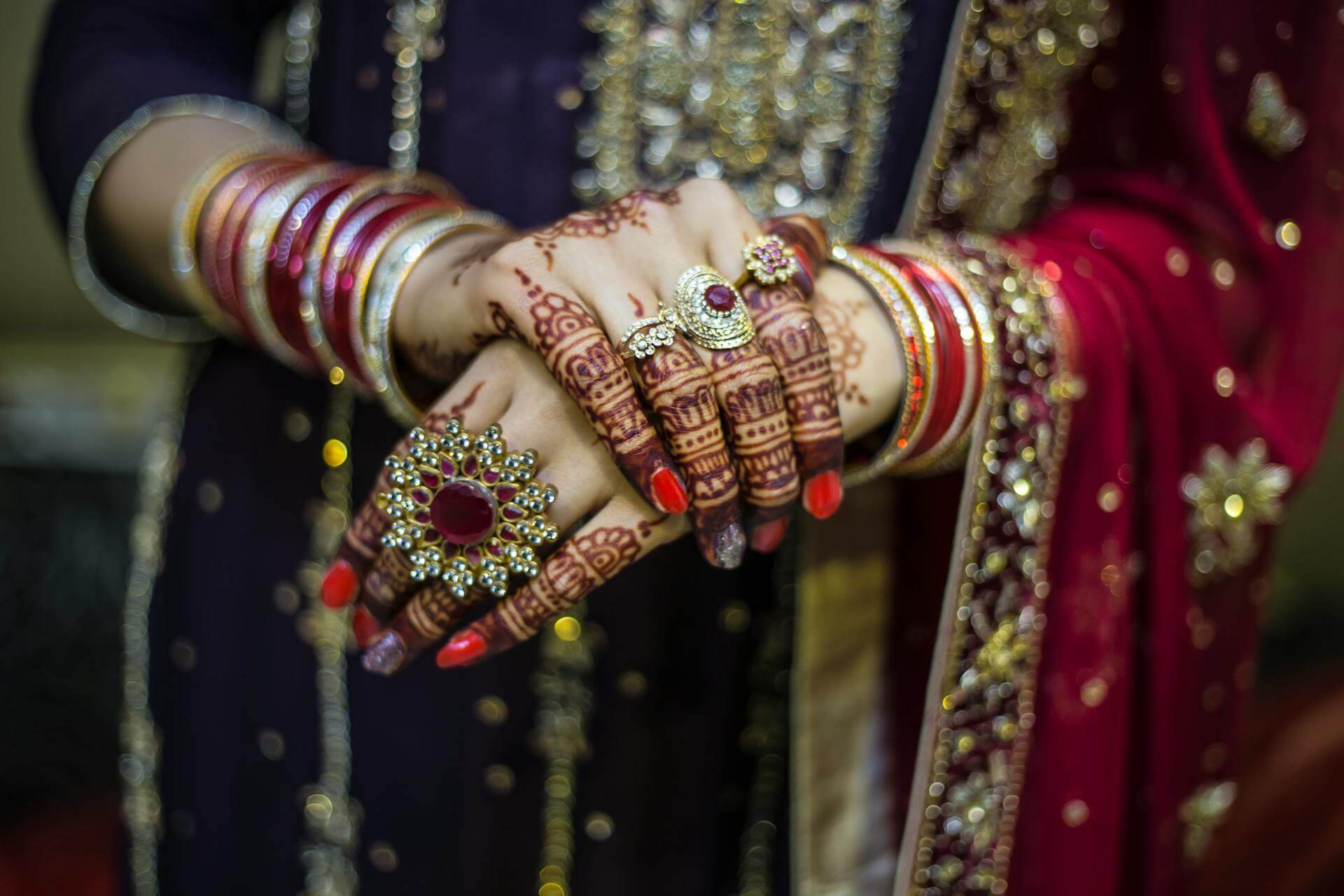 Henna design on the hand of an Indian bride adorned with jewels.