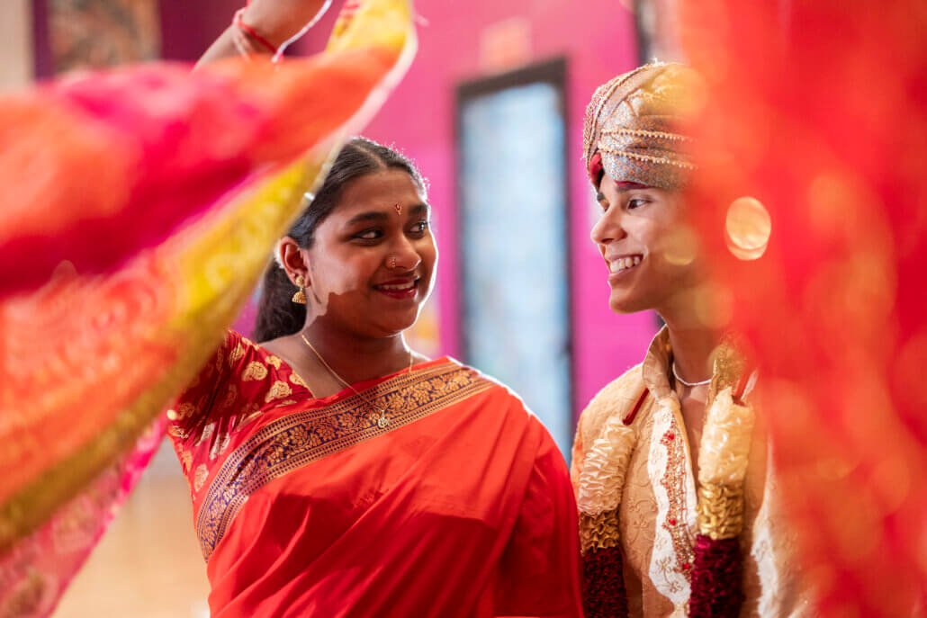 Hindu ceremony celebrating marriage with scarves near the camera, the young couple looks into each other's eyes