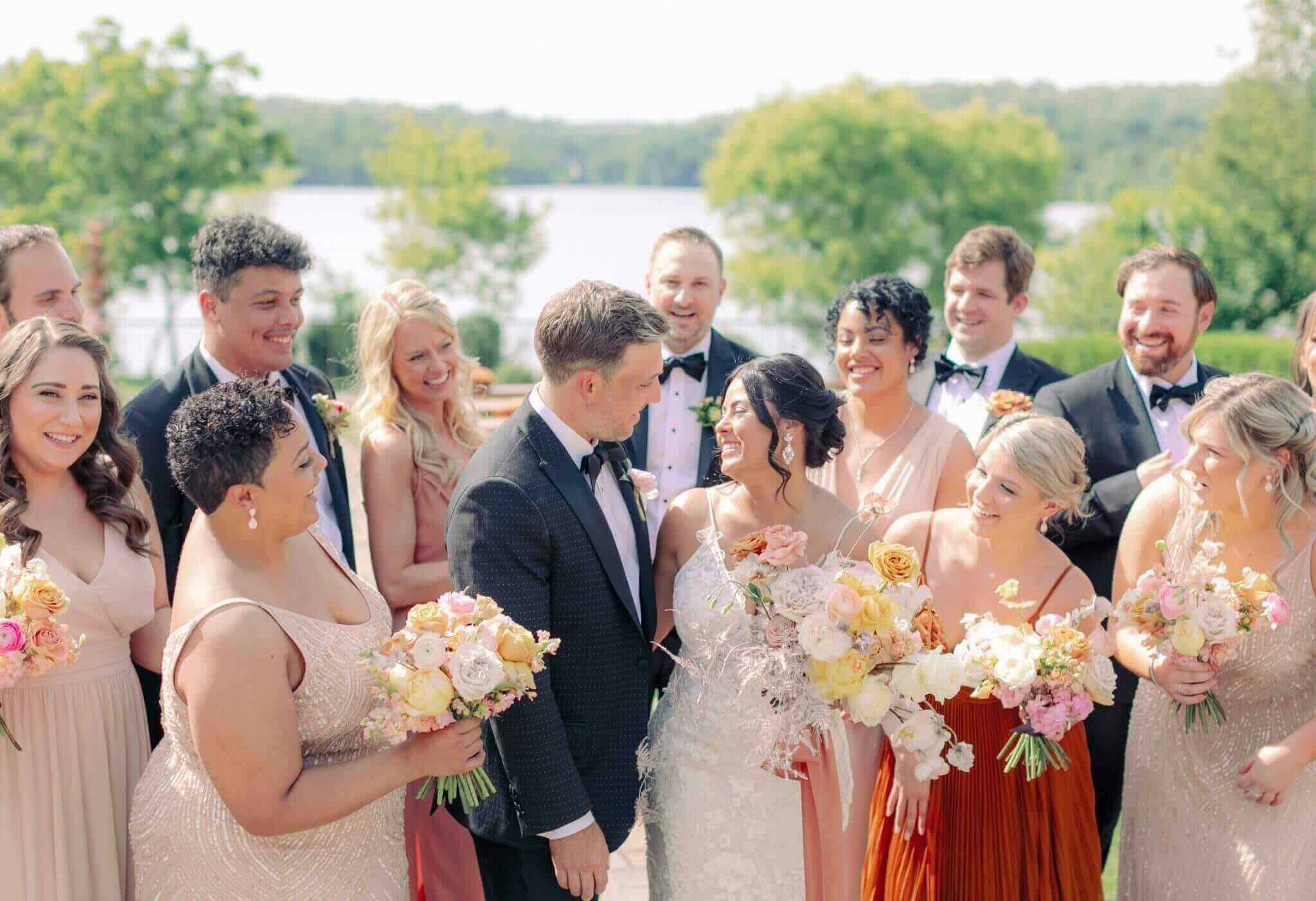 A group of bridesmaids and groomsmen standing in front of a lake during a wedding experience.
