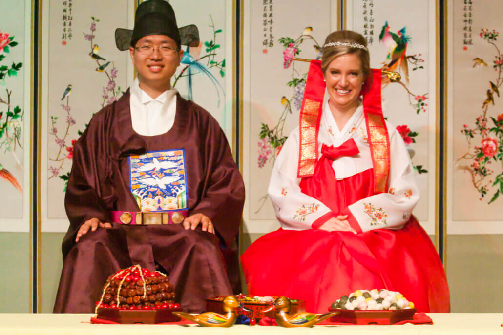 Korean man and caucasian woman taking part in traditional Korean Paebaek ceremony.