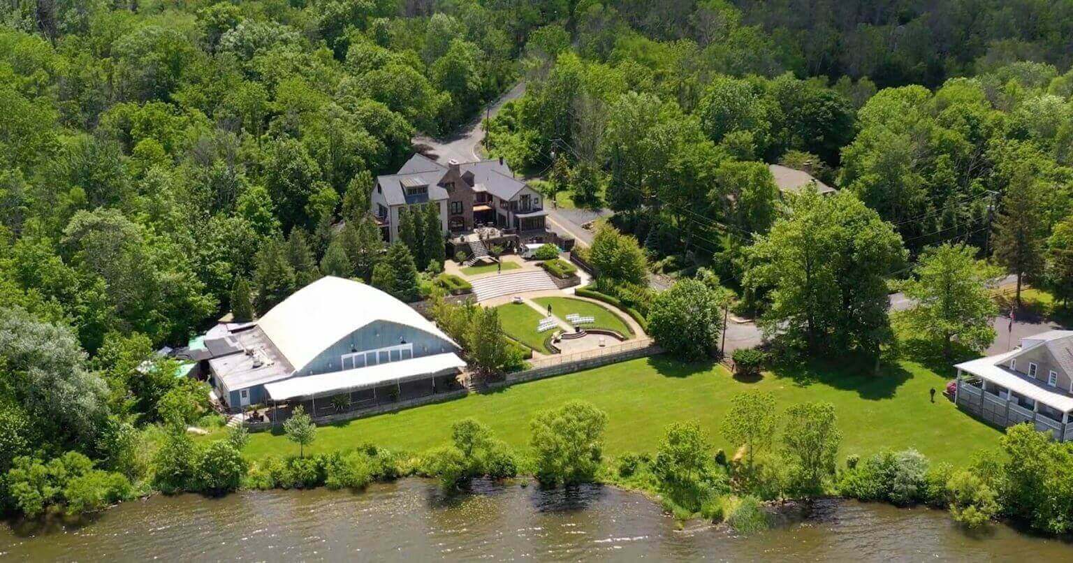 An aerial view of a large house on a lake, designed for an unforgettable wedding experience.