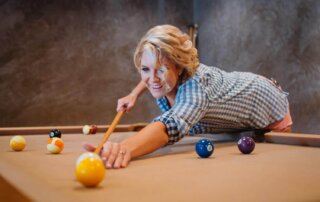 A woman playing billiards in her home.