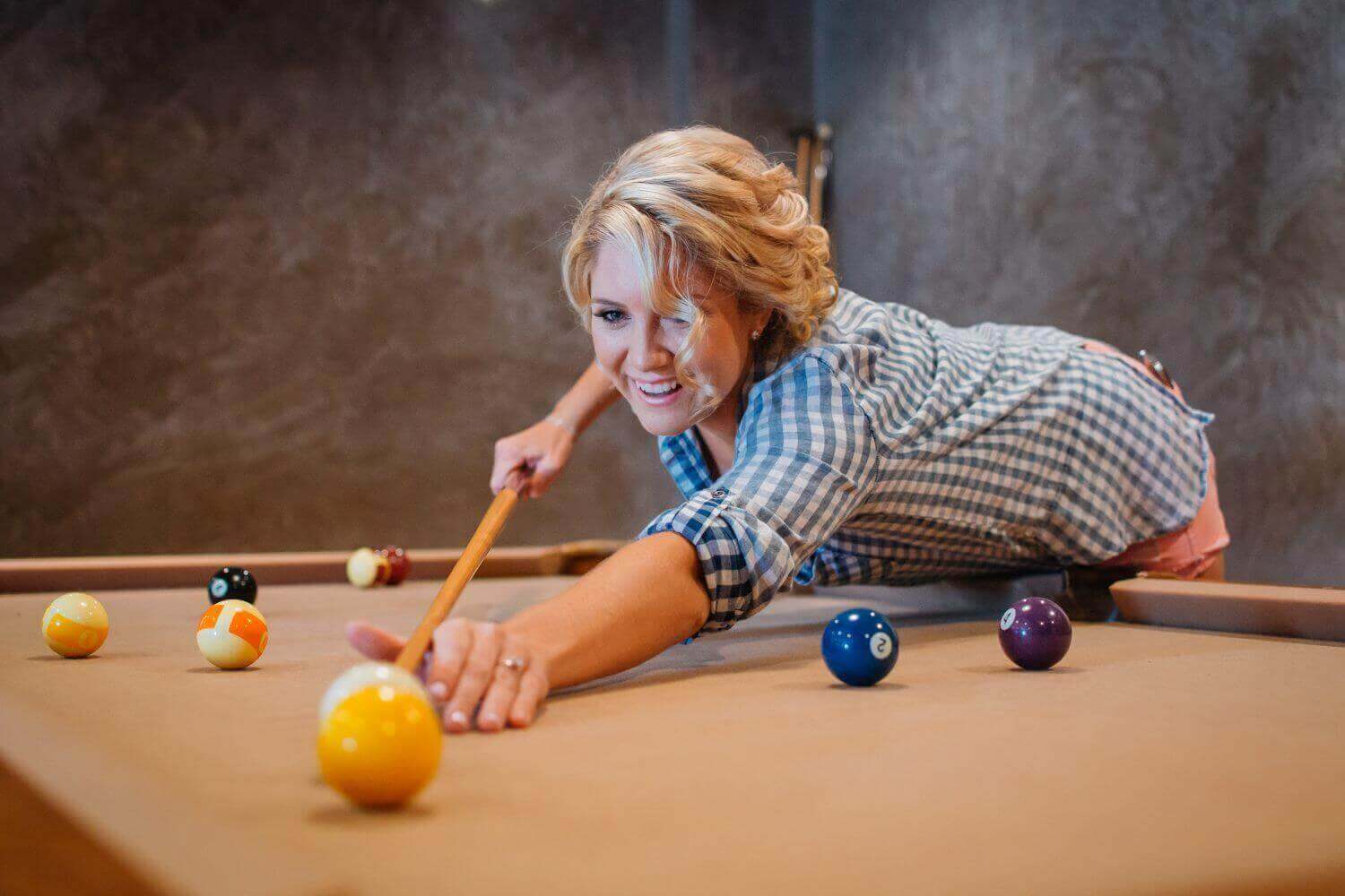 A woman playing billiards in her home.
